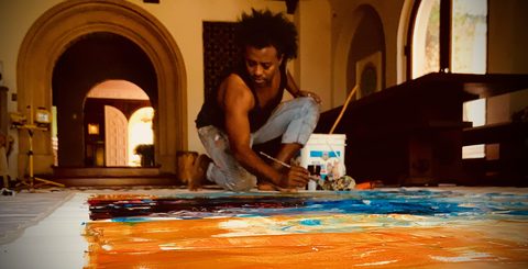 Yared Nigussu painting a long canvas at Daniel Lanois's home